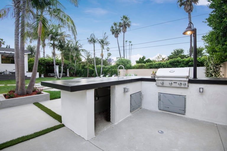 Outdoor kitchen with palm trees backdrop in a modern new construction home