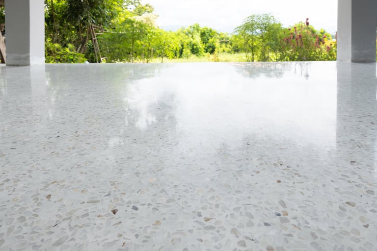Terrazzo style outdoor patio floor with clean white bright shiny surface reflecting green plants and sky