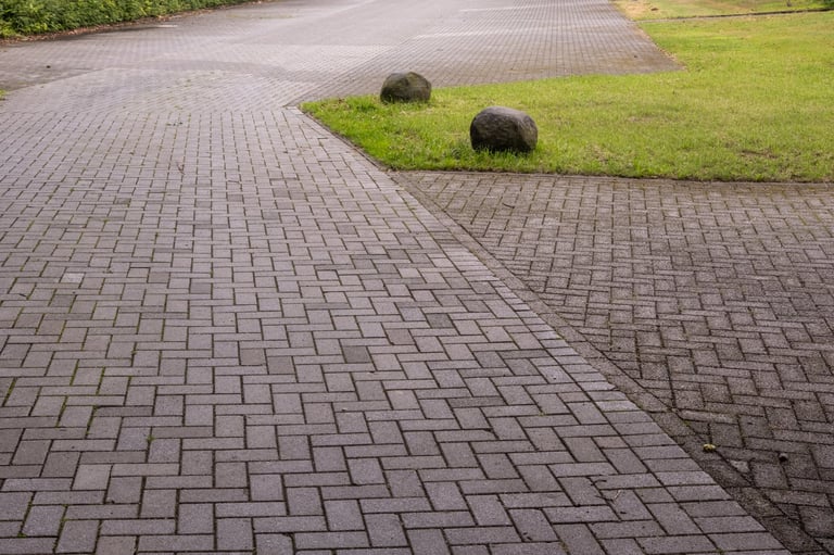 Pathway and parking area made of gray interlocking pavers with grass and rocks