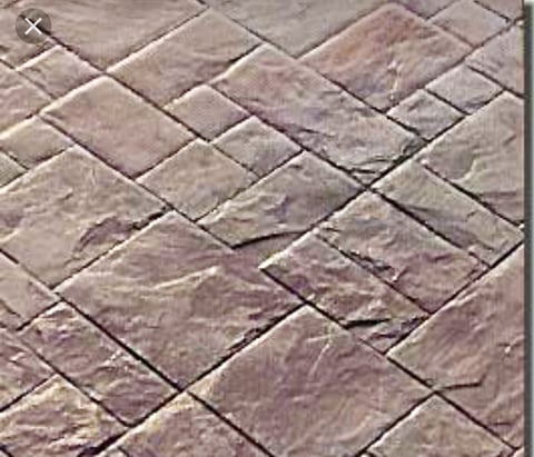 Close-up of herringbone pattern paving stones in shades of brown and gray with natural texture